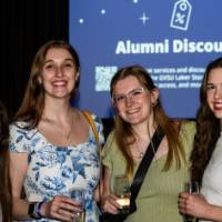 Four grads smile with champagne at Toast
